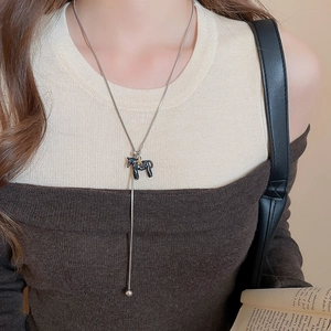Close-up of a silver snake chain necklace featuring a black pony pendant with a gold star