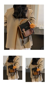 Detail of premium bicolor backpack with vintage strap buckle and plush teddy pendant