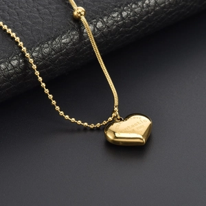 Golden heart necklace with snake chain and bead splicing on black leather background