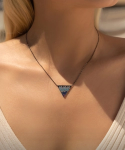 Dettaglio della collana con ciondolo a triangolo geometrico e gemme blu e viola
