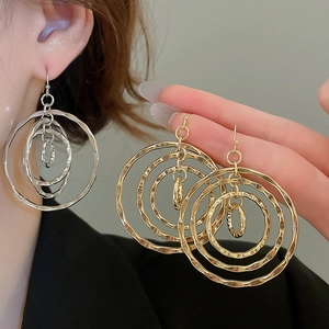 Close-up of geometric multi-layered gold and silver round earrings with hammered texture