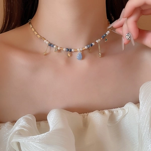 Détail du collier avec perles de cristal bleu et pendentifs dorés étoile et lune