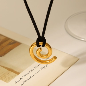 Macro shot of 18K gold spiral pendant necklace featuring a black silk cord detail