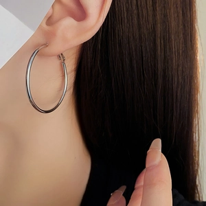 Close-up of a model wearing large silver round hoop earrings with metallic finish
