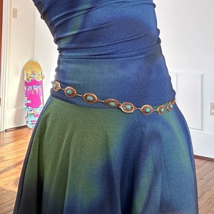 Detailed shot of bronze metal waist chain with sun-shaped rings and turquoise stones