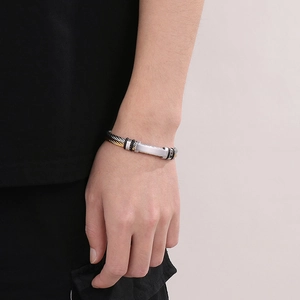 Close-up of men's two-tone stainless steel cable bracelet in silver and gold on wrist