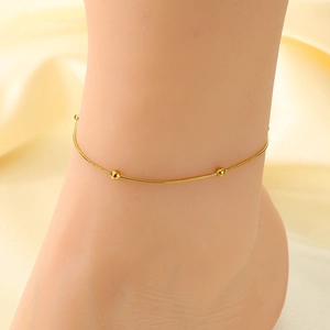 Chevillère élégante en maille serpent dorée avec perles sur la cheville d'une femme