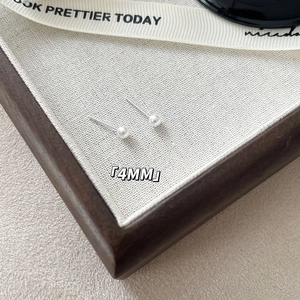 Detailed close-up of 4mm minimalist pearl earrings on ribbon with S925 silver needles