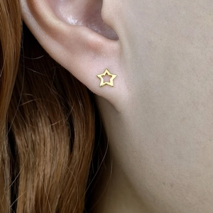 Detailed close-up of a minimalist hollow star stud earring in a gold finish