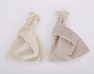 Detail view of soft cream and khaki velvet fabric wrist bags in a minimalist layout