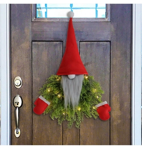 Detail of a lighted Christmas gnome wreath with red hat and LED lights on a wooden door