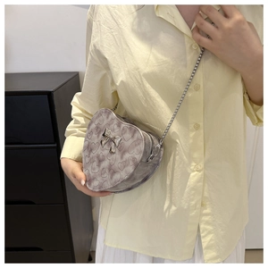 Detail of heart-shaped marble pattern crossbody bag with silver bow and chain strap