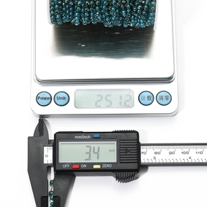 Macro view of 3.4mm faceted teal crystal bead chain on a spool with weight measurement