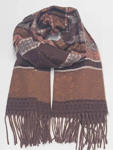 Detail of a brown cashmere-style scarf with intricate jacquard patterns and soft fringes