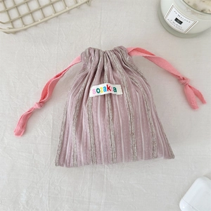 Detail of pink striped drawstring pouch with soft fabric texture and woven label