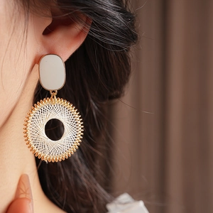Close-up of model wearing gold hoop earrings with white woven grid pattern details