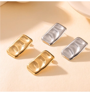 Detailed view of rectangular geometric earrings with hammer texture in gold and silver