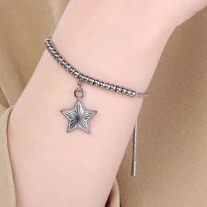 Detail shot of a beaded stainless steel bracelet with an engraved star charm on a wrist
