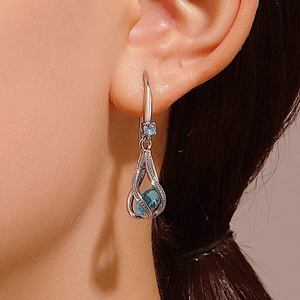 Silver teardrop earrings with light blue zircon crystals worn by a model
