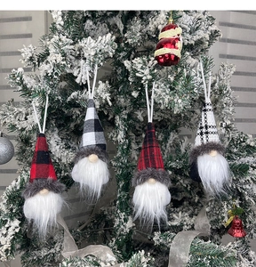 Close-up of Swedish Christmas gnomes with plaid hats hanging on a snowy tree branch