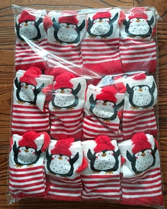 Detail view of bulk Christmas socks featuring red stripes and cartoon penguin patterns