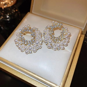 Macro shot of elegant gold circle earrings with pearls and rhinestones in a jewelry box