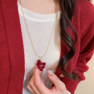 Detail of velvet grape pendant necklace on model with golden chain and burgundy finish