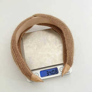 Detailed view of camel knit twist headband weighing 34.08g on a precision scale