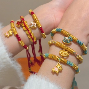 Detail of hand-woven red cord bracelet with gold beads and colorful enamel horse charm