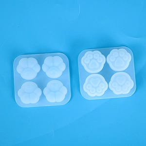Top view of two cat paw silicone molds with four cavities on a blue background