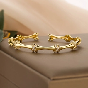Gold plated bamboo joint open cuff bracelet with zircon accents on dark jewelry box