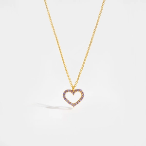 Macro detail of gold necklace with heart pendant featuring purple micro-paved crystals