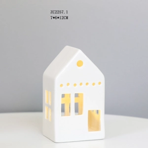 Detail of white ceramic LED house lamp with star cutouts and warm glowing light