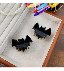 Macro detail of acrylic black bat hair claws with glitter finish in a gift box
