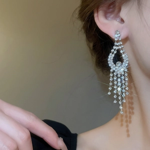 Detail of silver tassel earrings with sparkling rhinestones worn on a model for a gala