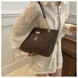 Close-up of brown checkered tote bag with gold chain strap and deer pendant charm