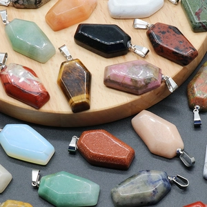 Mini natural crystal coffin pendants in rose quartz and tiger eye on a wooden tray