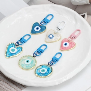 Turkish Evil Eye enamel keychains in heart and round shapes on a white ceramic tray