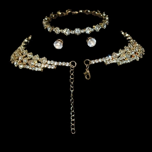 Detailed view of shiny gold necklace and earring set with crystals on black background