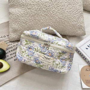 Close-up of quilted floral makeup bag with sturdy handle and dual metal zippers