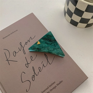 Close-up of dark green marble pattern triangle hair claw clip with gold pendant