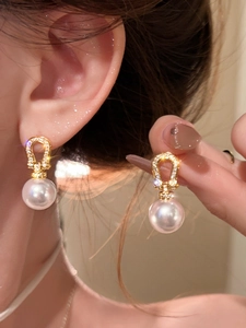 Close-up of 18K gold plated horseshoe earrings with sparkling zircon and white pearls