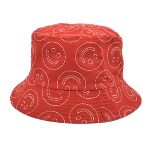 Detail of red cotton bucket hat with white embroidered smiley face and stitching