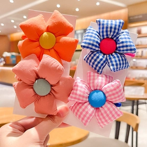 Detail of four fabric flower hair ties featuring solid colors and checkered patterns