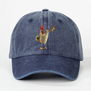 Close-up of a washed denim baseball cap with a cartoon rooster print on white background