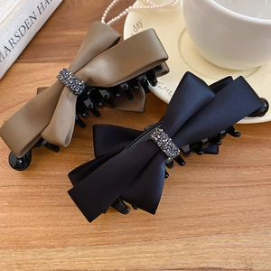 Detail view of satin bow hair claws with sparkling beads on a warm wooden background