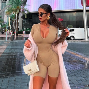 Close-up of beige V-neck bodycon romper with front zipper detail and pink plush jacket