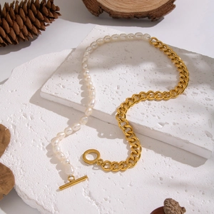 Elegant pearl and gold chain necklace with toggle clasp on a natural stone base