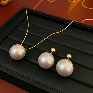 Detailed view of large cream pearls necklace and matching earrings on black jewelry tray