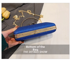 Detailed bottom view of dark blue glitter evening clutch with gold metal frame and chain